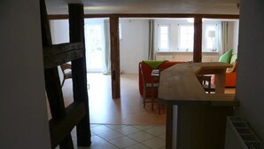 Una habitación con una mesa de madera, un sofá rojo y una ventana con cortinas.