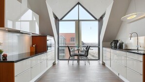 Una cocina moderna con un ventanal amplio, un comedor y vistas a la ciudad.