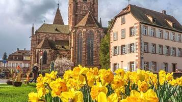 Eine Kirche mit einem hohen Kirchturm und ein Gebäude mit einem geneigten Dach im Vordergrund.