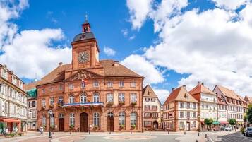 Ein historisches Gebäude mit einem Uhrturm, großen Fenstern und einem zentralen Eingang.