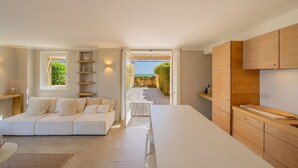 A modern kitchen with wooden cabinets, a white countertop, and a view through an open door to a patio. - Charming house - AC/2 BR/4P - Saint-Tropez (Saint-Tropez)