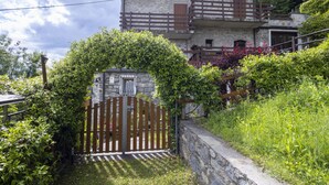 A stone building with a wooden balcony and a gate surrounded by greenery. - Moncucco Mountain Home by Interhome (Valtellina)
