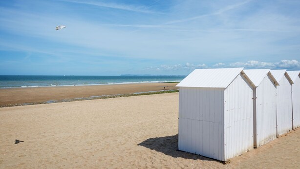 A beach with white beach huts and a clear sky. - Les Marines by Interhome (Villers sur mer)