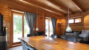 L’intérieur d’un chalet en bois comprend une table à manger, des chaises, un canapé et une cheminée.