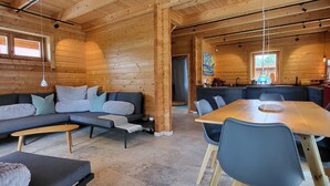 L’intérieur d’un chalet confortable, avec un canapé, une table à manger et un coin cuisine.