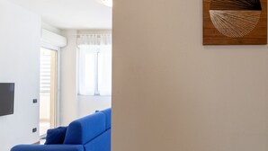 Una sala moderna con un sofá azul, un televisor de pantalla plana montado en la pared y una obra de arte de madera.