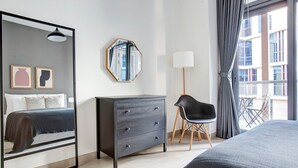 Una habitación de hotel moderna con una cama grande, un aparador, una silla y un espejo.