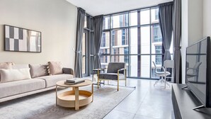 Una sala de estar moderna con sofá, sillón, mesa de centro y televisor.