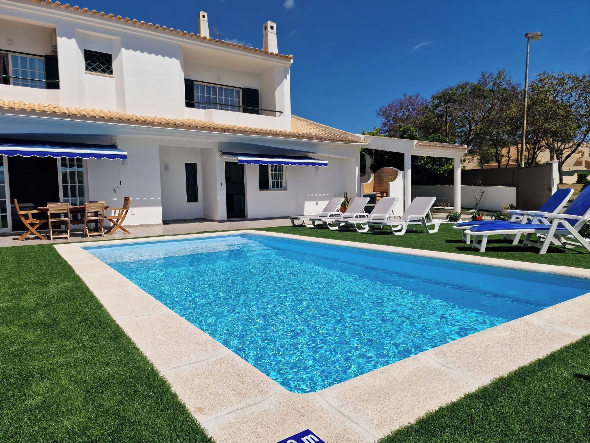 Ein Pool mit Liegestühlen, ein Patio-Tisch und ein überdachter Bereich mit Sonnenschirmen.