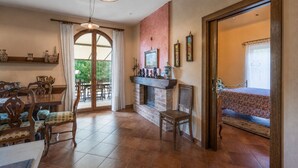 Un coin repas comprenant une table et des chaises, une cheminée et une vue à travers une porte vitrée.