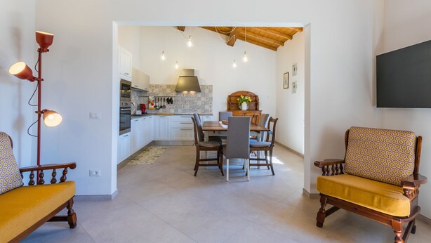 Un salon moderne avec un coin repas, des meubles en bois et une cuisine en arrière-plan.