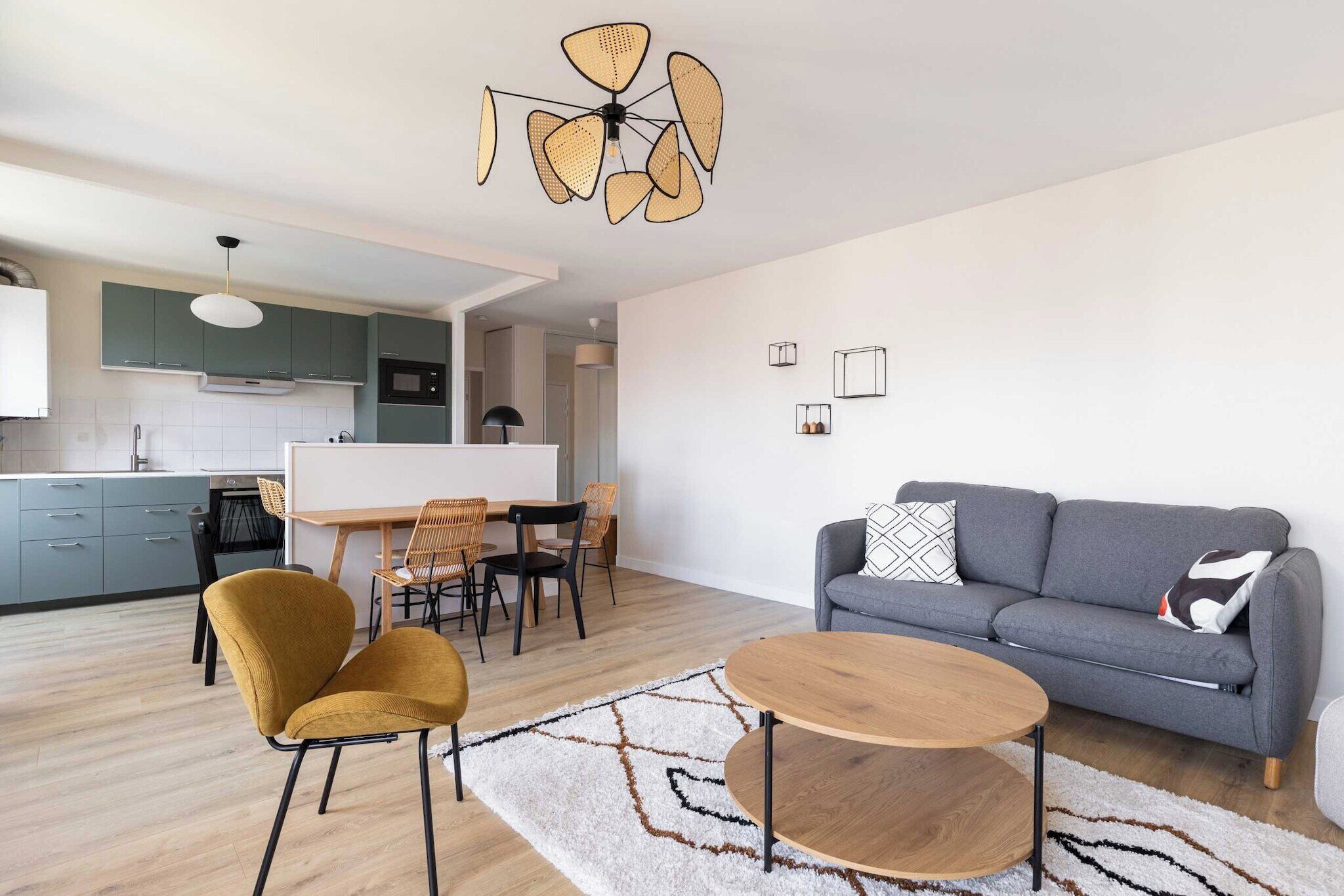 A modern living room with a grey sofa, mustard chairs, a wooden coffee table, and a dining area with a white table and chairs.