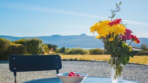 A table with a book, a bowl of strawberries, and a vase of flowers.