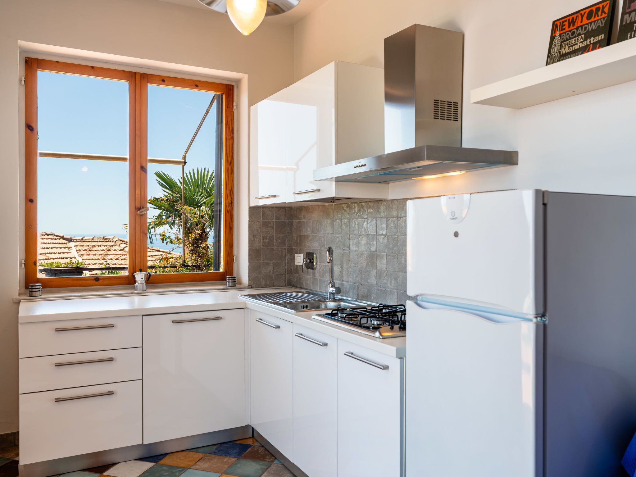 A modern kitchen with white cabinets, a stainless steel range hood, and a built-in refrigerator.