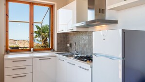 A modern kitchen with white cabinets, a stainless steel range hood, and a built-in refrigerator.
