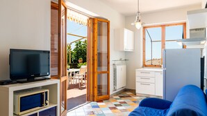 A compact living space with a television, kitchenette, and a sofa.