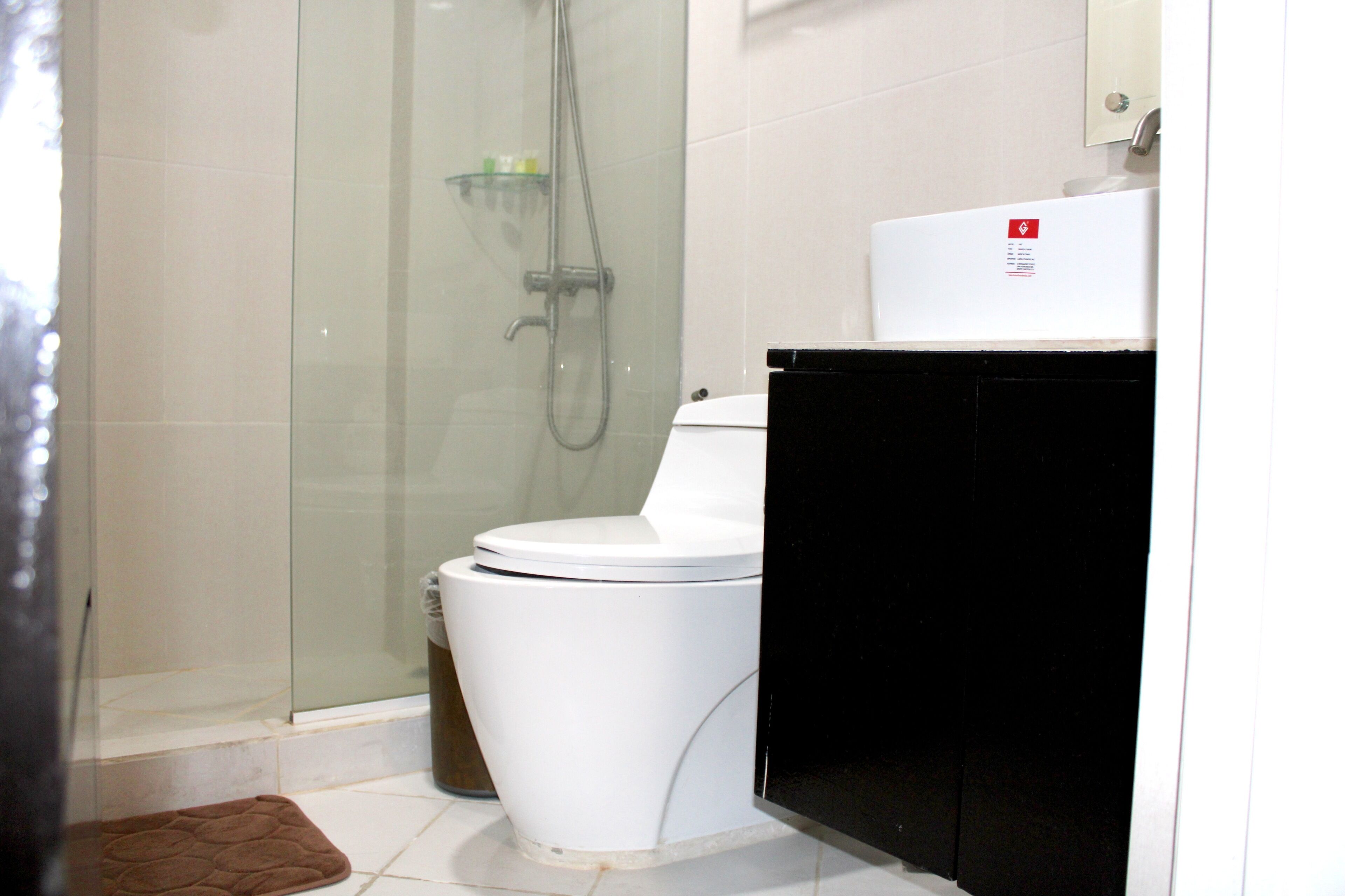 A bathroom with a glass-enclosed shower, a white toilet, and a black cabinet.