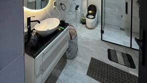 Ein modernes Badezimmer mit Waschtisch, großem Spiegel, Toilette und Duschbereich.