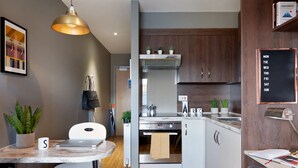 A modern kitchen with white cabinets, a built-in oven, and a wooden countertop. There is a hanging light fixture above the kitchen island. - For Students Only - Modern Rooms in Lincoln (Lincoln)