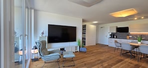 Un salon moderne doté d’un téléviseur à écran plat, d’un canapé et d’un coin repas avec des chaises.