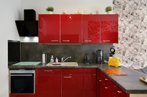 A kitchen with red cabinets, a black range hood, a microwave, a coffee maker, and a toaster.