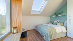 A bedroom with a skylight, a bed with a striped blanket, a wooden floor, and a wall-mounted shelf. - "Haffhus" Vacation Home with a Balcony, Terrace, and 2 Bathrooms - Modern Vacation Home (Usedom)
