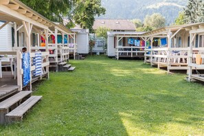 A campground with wooden cabins, each with a porch and a small table. - Mobile Home Bodensdorf Near Gerlitzen Ski Area (Steindorf am Ossiacher See)