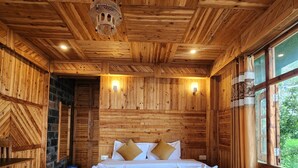 A wooden room with a large bed, two wall-mounted lights, and a window with curtains. - Talaighar Farmstay Shimla (Fagu)