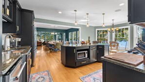 Une cuisine moderne avec des meubles de couleur sombre, des plans de travail en granit et un îlot central.