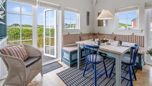 A bright kitchen with a dining table, blue chairs, and a view of the countryside.