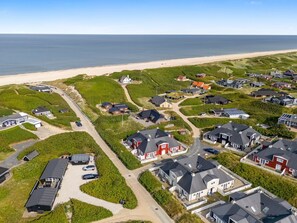 An aerial view of a coastal residential area with houses, roads, and a beach.