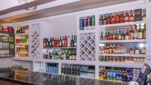 A bar area with shelves stocked with various alcoholic beverages and snacks. - Holiday Premier Hotel (Ol Kalou)