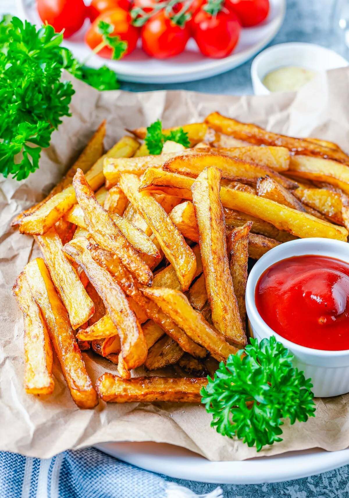 A plate of golden-brown French fries with a side of ketchup.