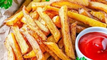 A plate of golden-brown French fries with a side of ketchup.