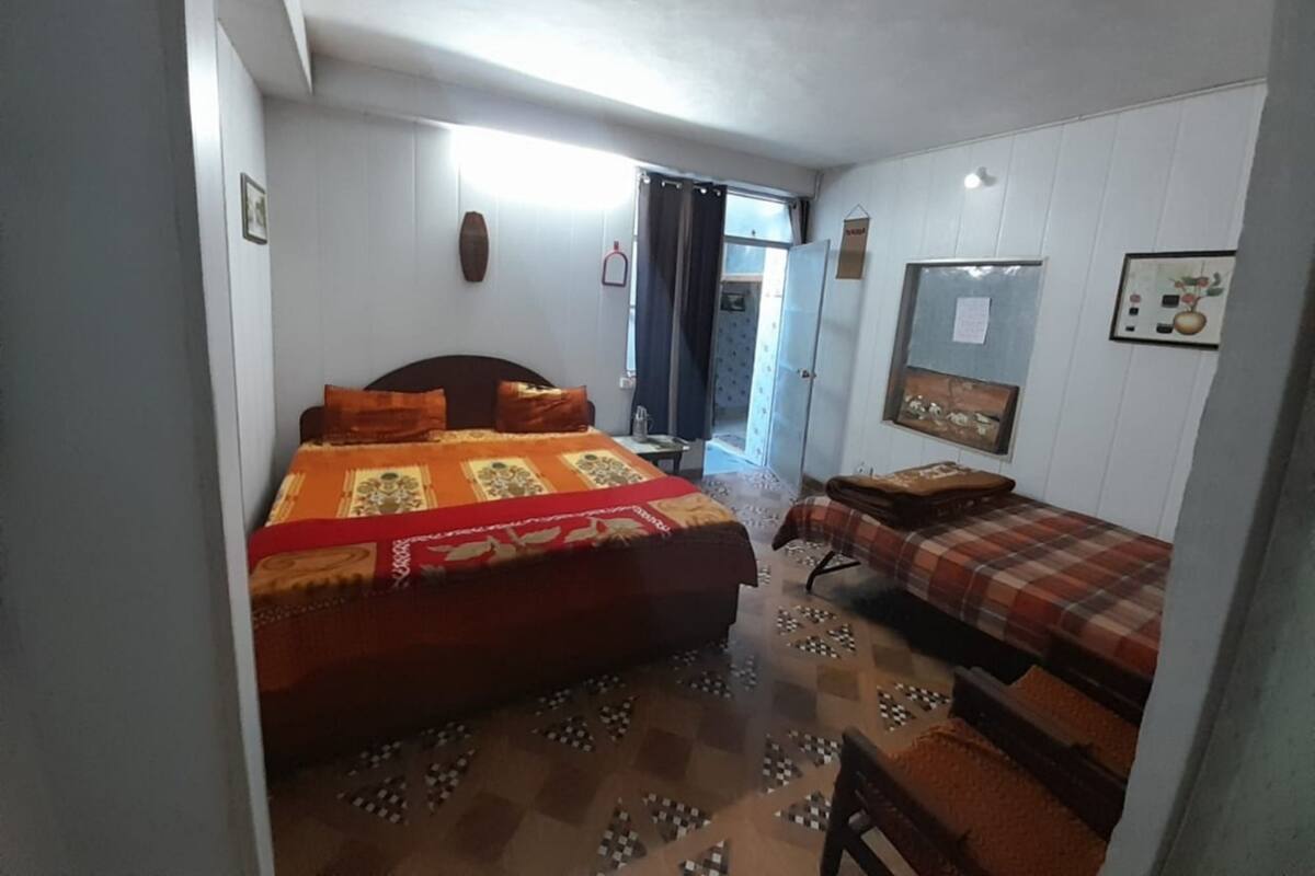 A bedroom with a large bed, a smaller bed, a chair, and a desk.