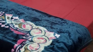 A bed with a red bedspread and a blue blanket with a floral pattern. - Kaushik Cottage (Mussoorie)
