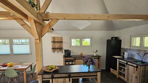A modern kitchen with wooden beams, a central island, and a dining area with green chairs.