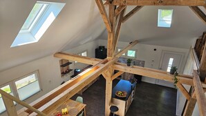 A spacious loft with high ceilings, exposed wooden beams, and skylights.