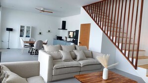 A modern living room with a sofa, coffee table, and a staircase with wooden railings.