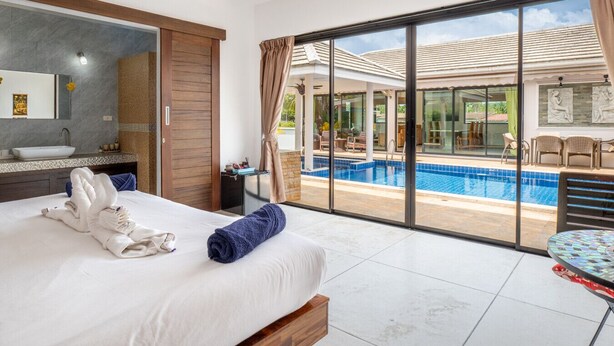 Une chambre d’hôtel avec un grand lit, une salle de bain et une vue sur une piscine.