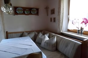 Een kamer met een bed, een bankje, een raam met uitzicht en een plank met borden.