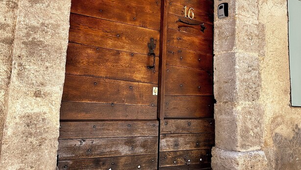 A large wooden double door with a brass handle, set in a stone wall with a small step leading up to it. - ✨ Cosy nest in the heart of Pézenas - Comfort & charm by Sandro (Pézenas)