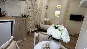 A compact living space with a kitchenette, a dining area with a white table and chairs, a sofa, and a TV mounted on the wall. - ✨ Cosy nest in the heart of Pézenas - Comfort & charm by Sandro (Pézenas)