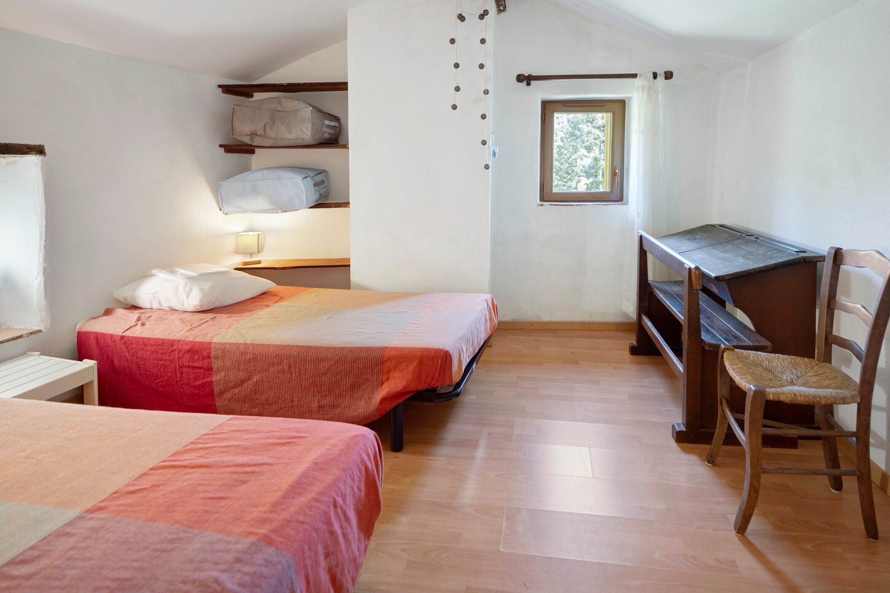 Een slaapkamer met twee bedden, een bureau, een stoel en een raam.