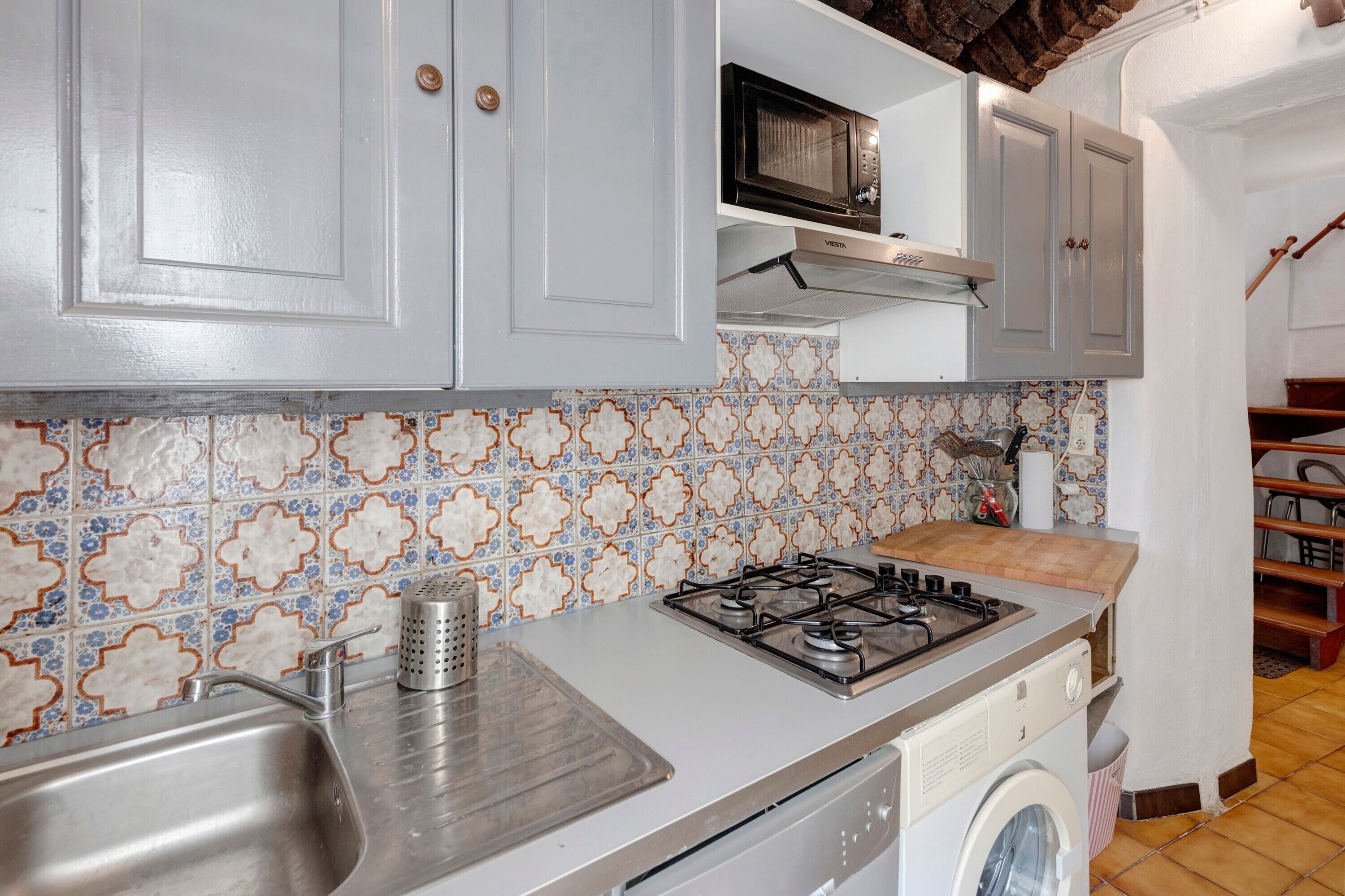 A kitchen with a gas stove, a microwave, a washing machine, and a sink.