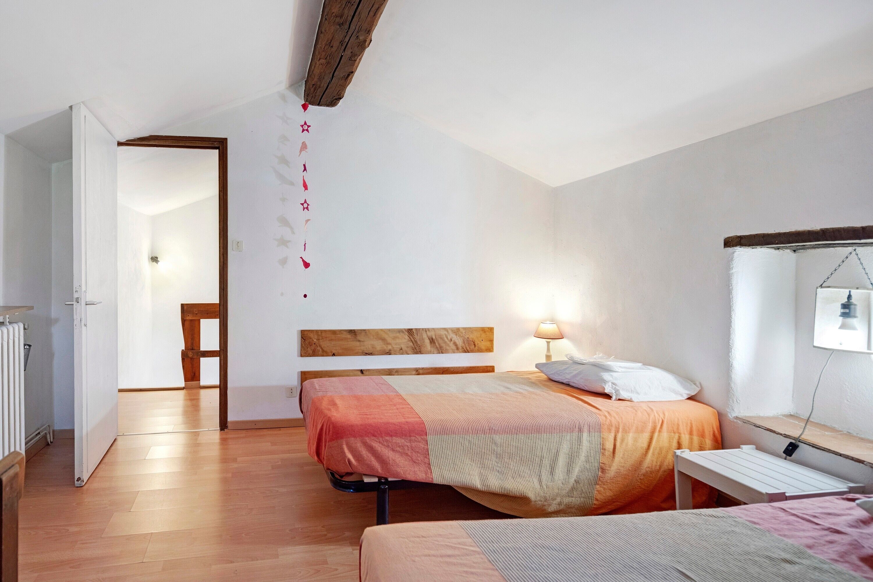 A bedroom with a wooden headboard, a bed with a striped blanket, a bedside table with a lamp, and a white radiator.