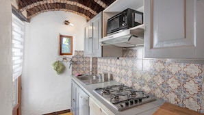 Una cucina compatta con piano cottura a gas, microonde e lavatrice.