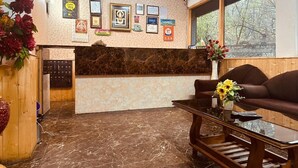 Zona de recepción con suelo de mármol, mostrador de recepción, un sofá y una mesita de centro.