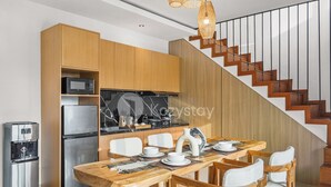 Una cocina moderna con armarios de madera, microondas integrado y refrigerador de acero inoxidable.
