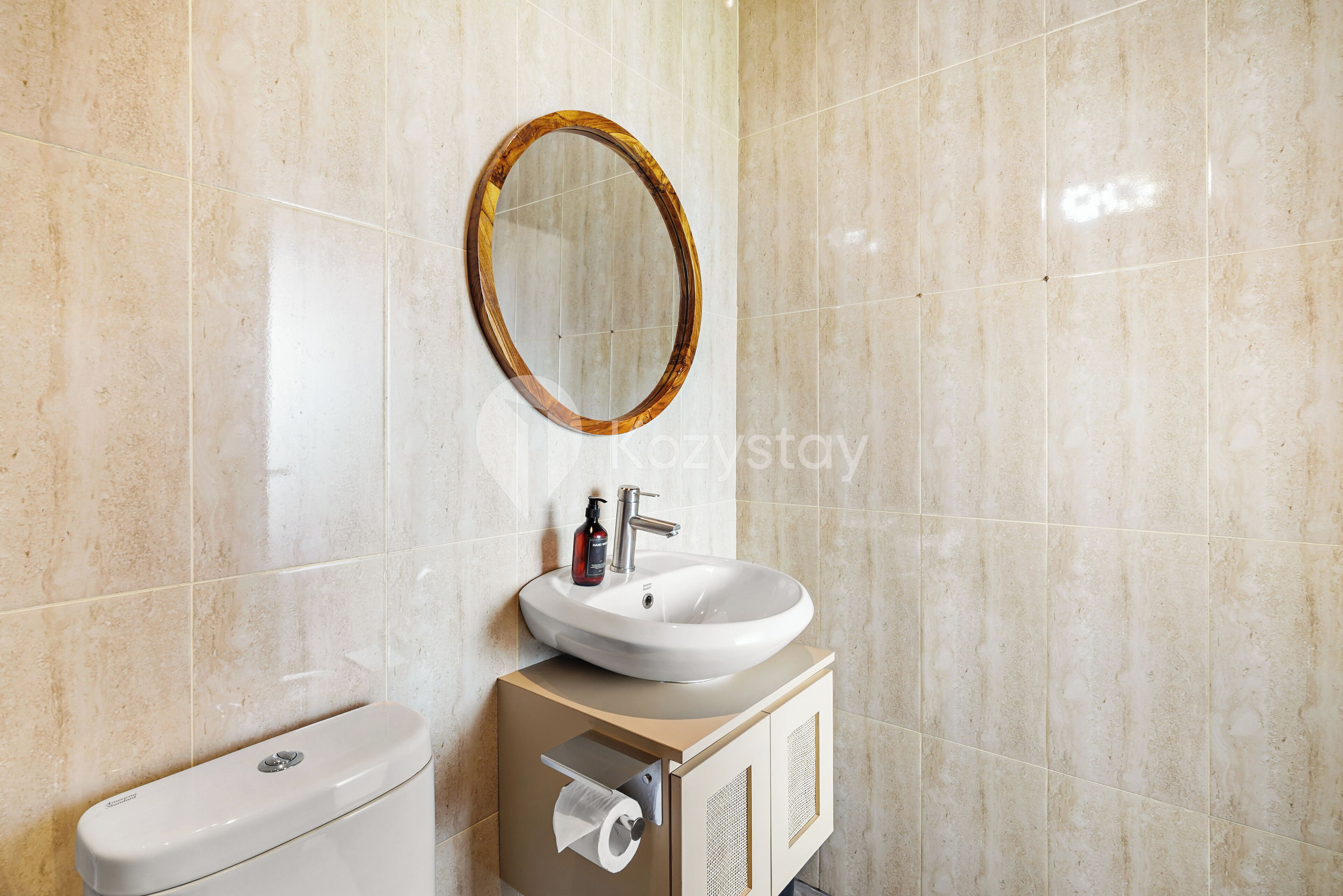 Un baño con un lavamanos blanco, un espejo redondo y un inodoro.